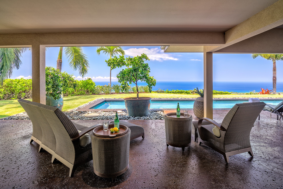 Photo of an expansive classic back patio in Hawaii with a water feature, concrete slabs and a roof extension.