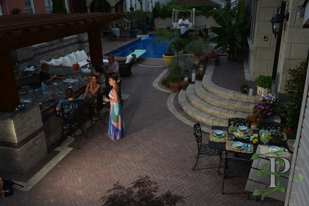 Cette image montre une terrasse arrière design de taille moyenne avec une cuisine d'été, des pavés en béton et une pergola.