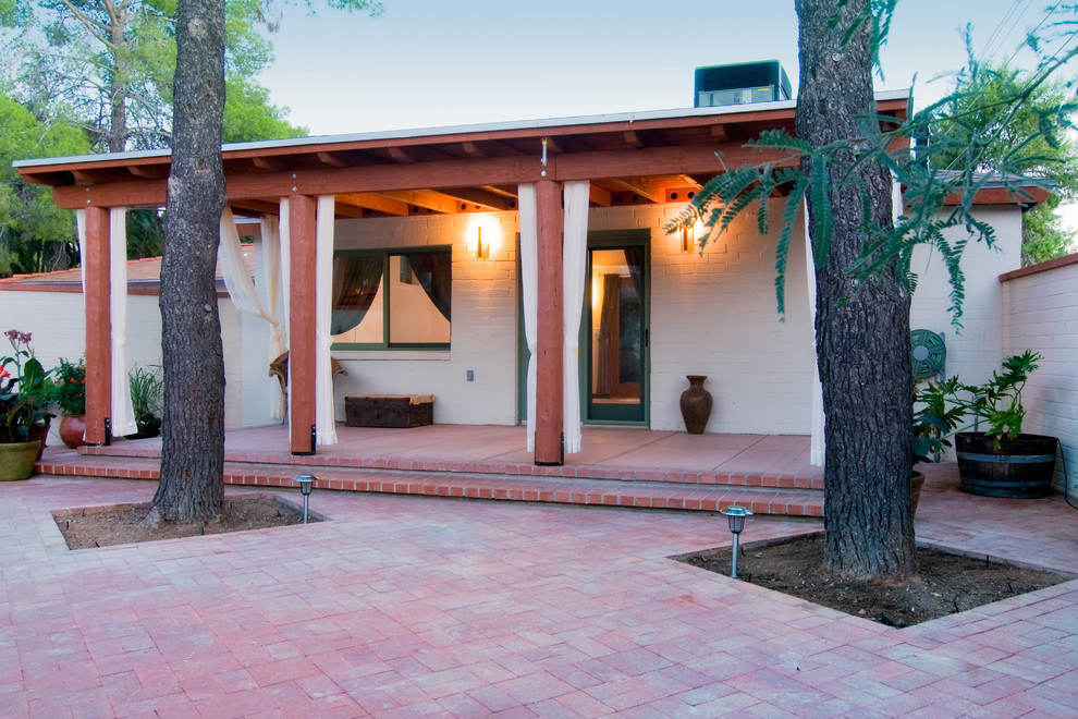 Aménagement d'une terrasse sud-ouest américain avec une cour, des pavés en brique et une extension de toiture.