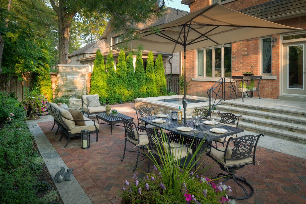 Design ideas for a large contemporary back patio in Toronto with an outdoor kitchen, brick paving and no cover.