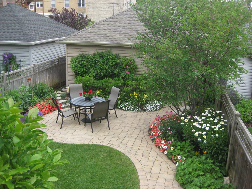 Foto di un patio o portico chic dietro casa e di medie dimensioni con pavimentazioni in mattoni e nessuna copertura