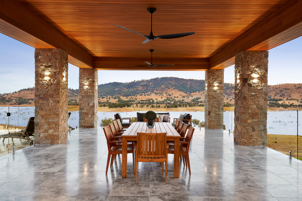 Cette image montre une très grande terrasse design avec une extension de toiture.