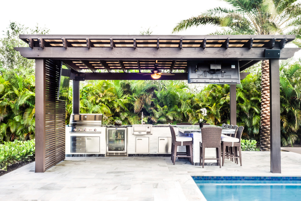 Exemple d'une grande terrasse arrière tendance avec une cuisine d'été, une pergola et des pavés en pierre naturelle.