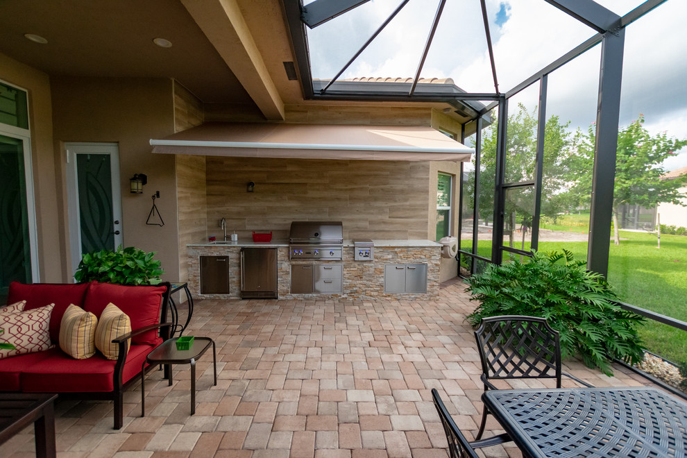 Cette image montre une terrasse arrière traditionnelle avec une cuisine d'été, des pavés en brique et un auvent.