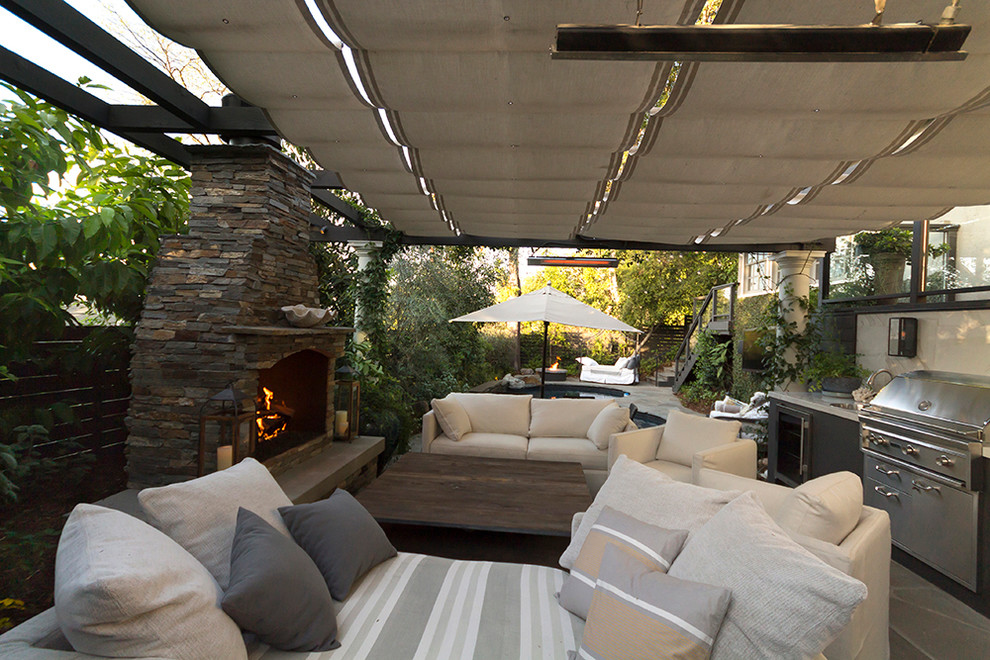 Inspiration pour une grande terrasse arrière minimaliste avec une cuisine d'été, des pavés en pierre naturelle et une pergola.