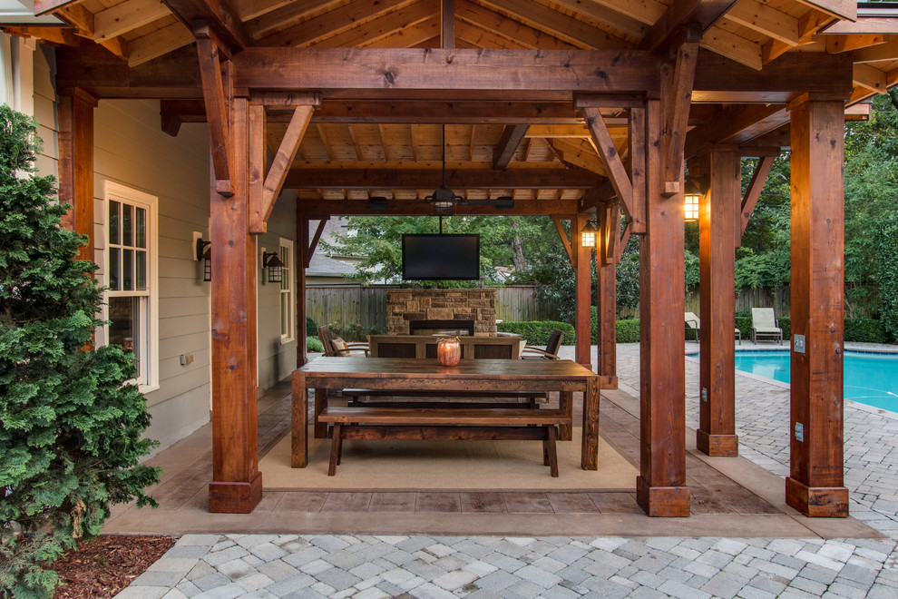 Esempio di un grande patio o portico stile rurale dietro casa con pavimentazioni in mattoni, una pergola e un focolare