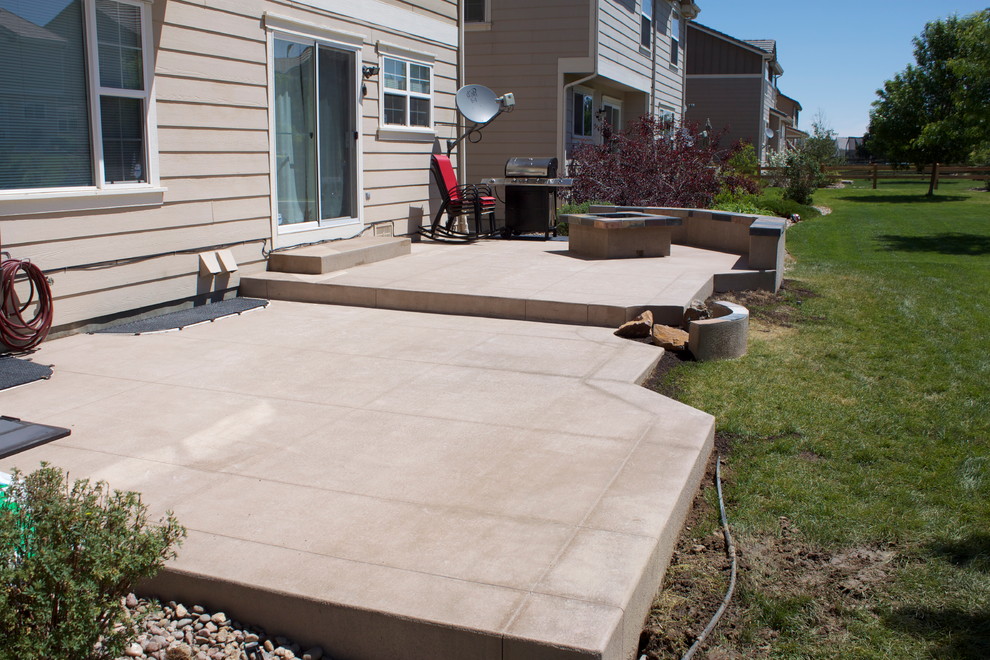 Inspiration for a large contemporary backyard stamped concrete patio remodel in Denver with a fire pit and no cover