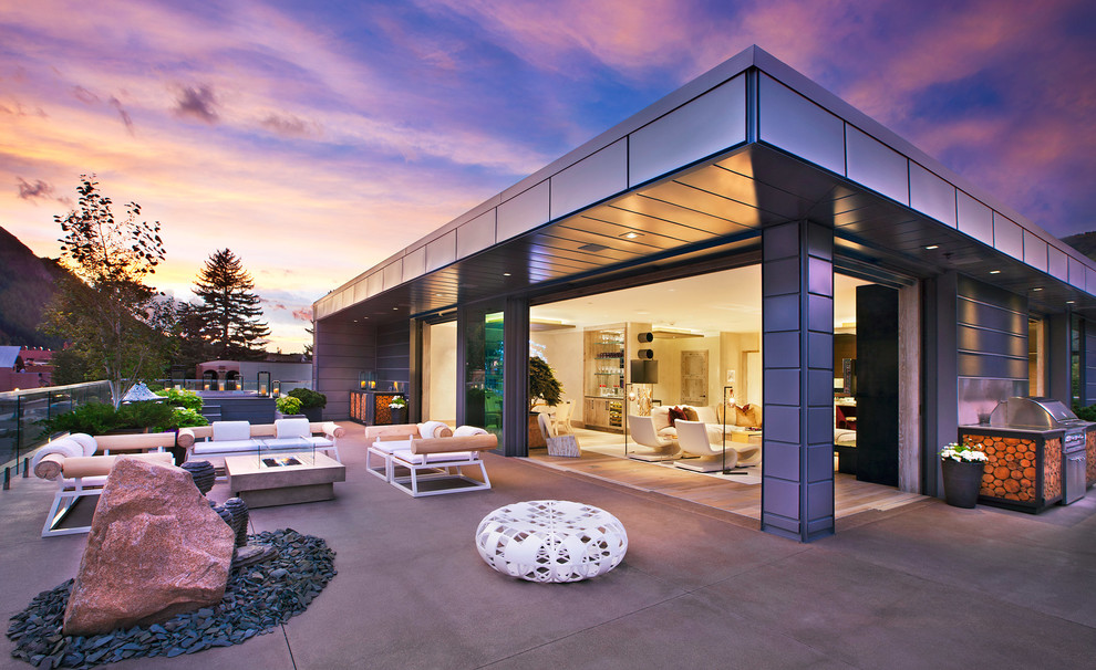 Réalisation d'une terrasse design avec un foyer extérieur, une dalle de béton et aucune couverture.