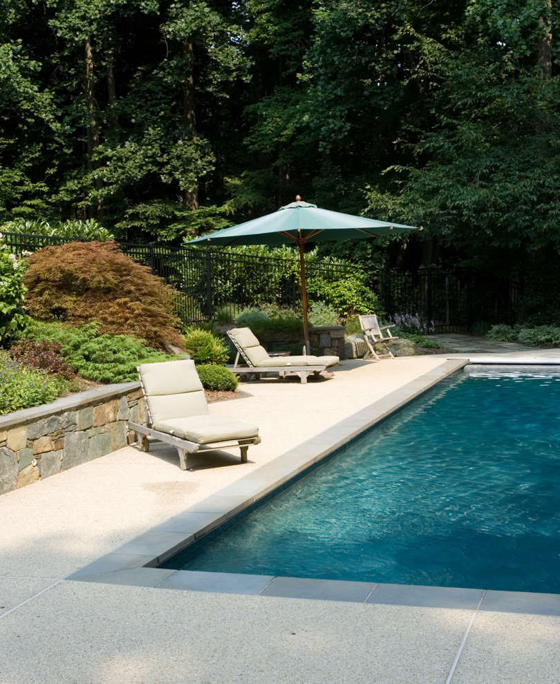 Ejemplo de piscina clásica de tamaño medio en patio trasero con granito descompuesto