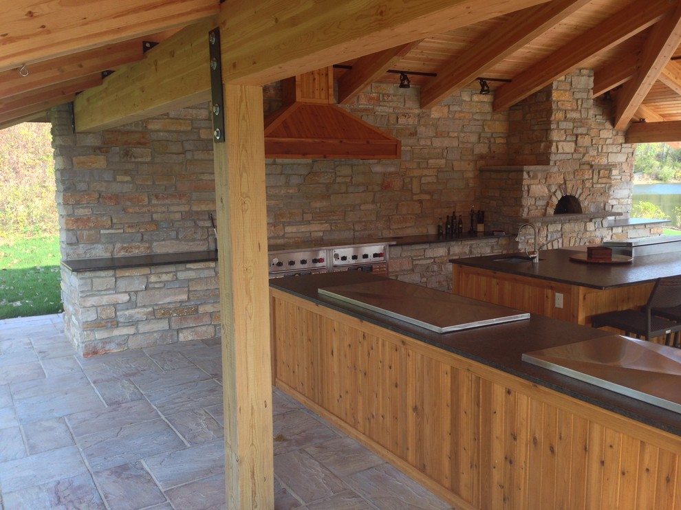 Photo of an expansive rustic patio in Chicago with an outdoor kitchen, brick paving and a gazebo.