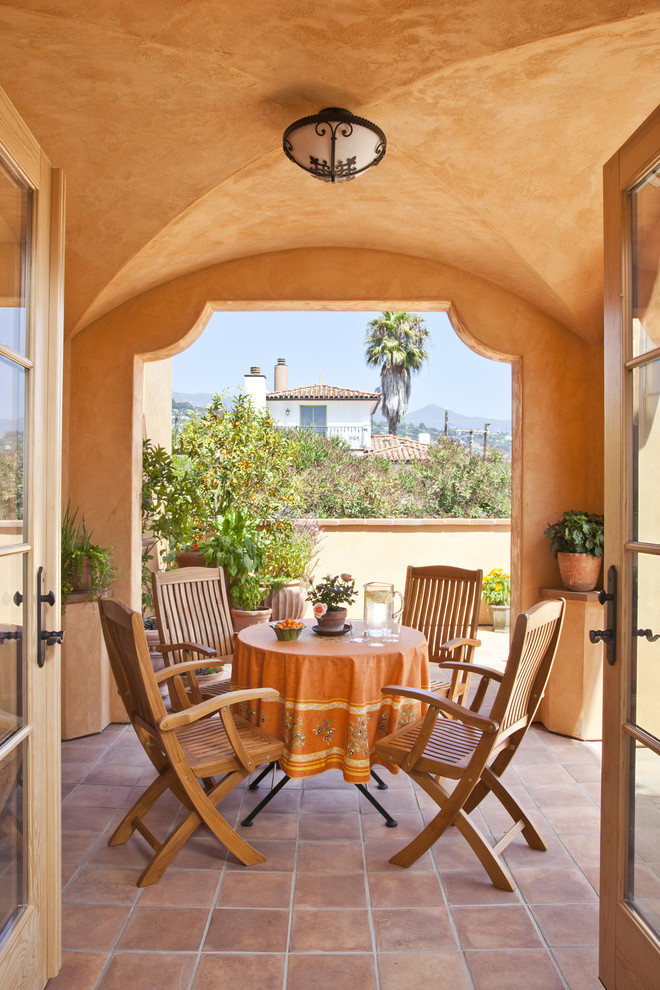 Photo of a mediterranean patio in Santa Barbara with tiled flooring and a roof extension.
