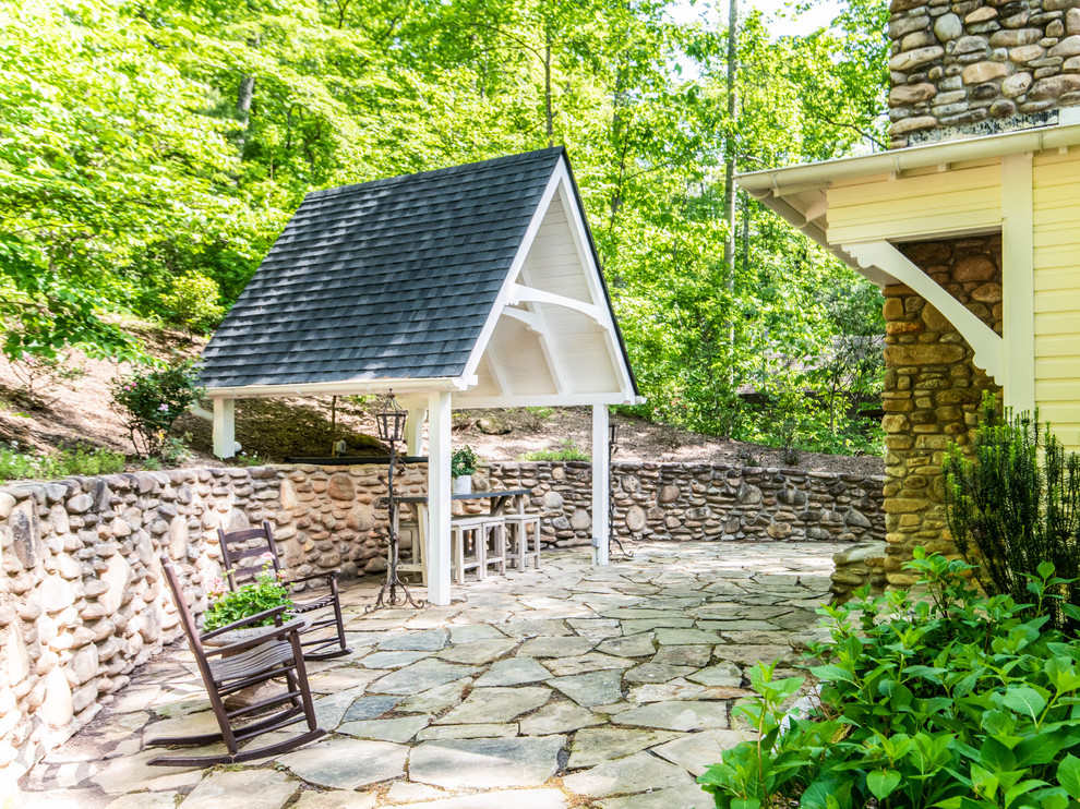 Ejemplo de patio de estilo de casa de campo de tamaño medio en patio trasero con chimenea, adoquines de piedra natural y cenador