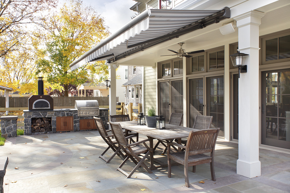 Imagen de patio clásico de tamaño medio en patio trasero con cocina exterior, losas de hormigón y toldo