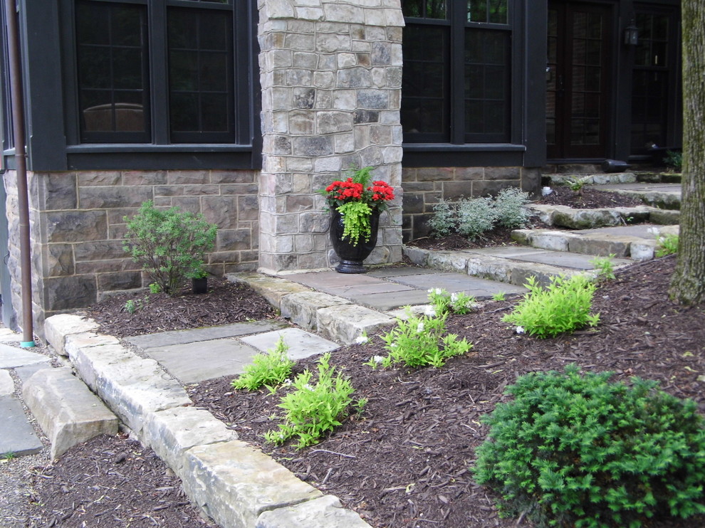 Photo of a large victorian back patio in Other with a potted garden, natural stone paving and no cover.