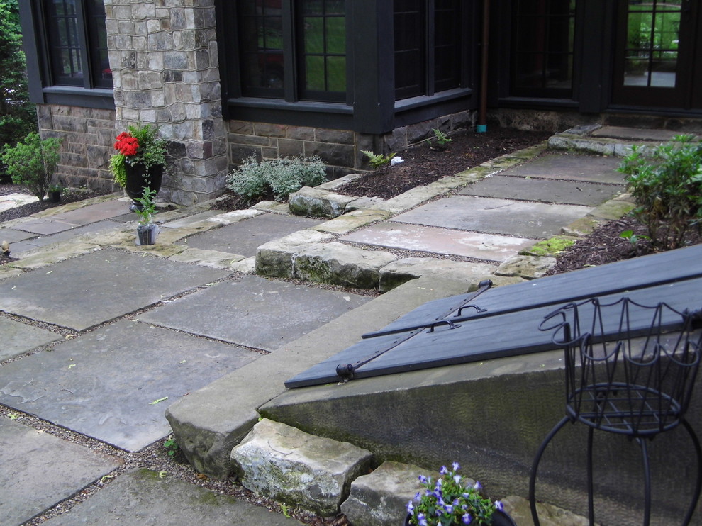 This is an example of a large victorian back patio in Other with a potted garden, natural stone paving and no cover.