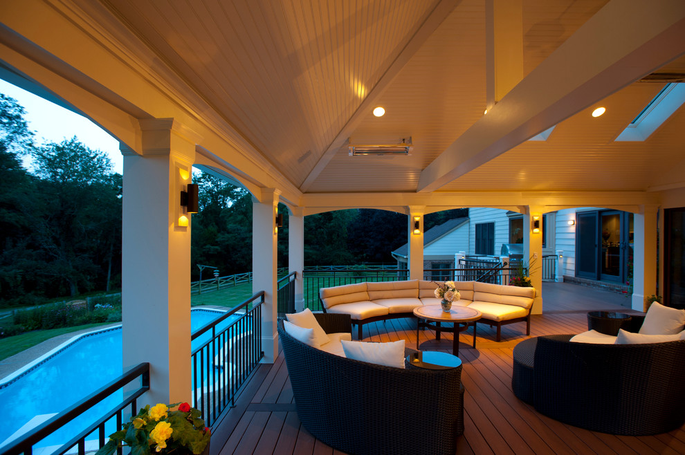 Cette image montre une grande terrasse arrière traditionnelle avec une cuisine d'été et une extension de toiture.