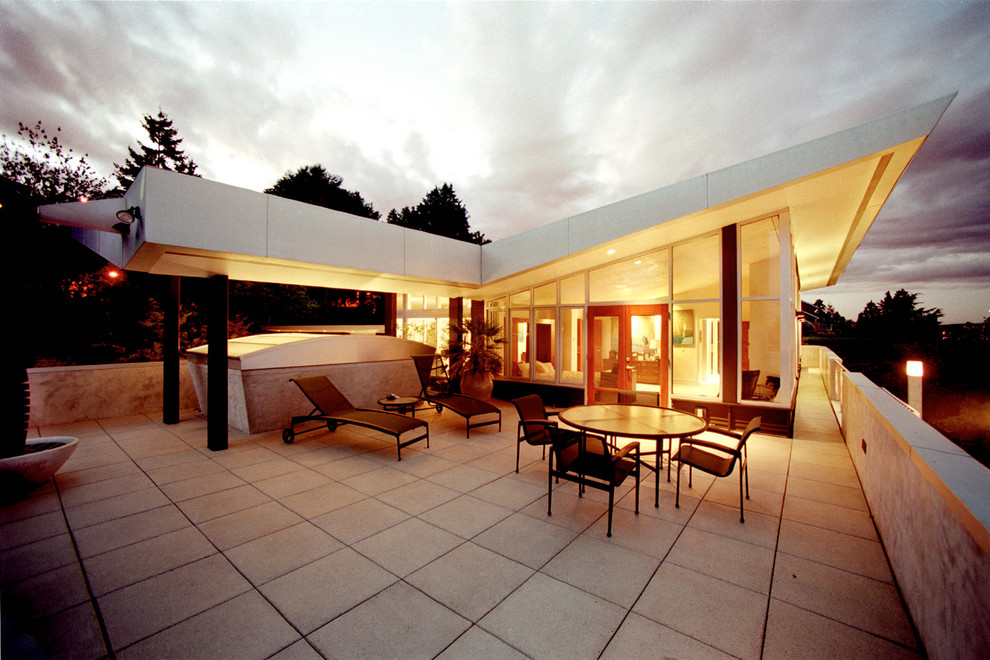 Example of a large minimalist concrete paver patio design in Seattle with a roof extension