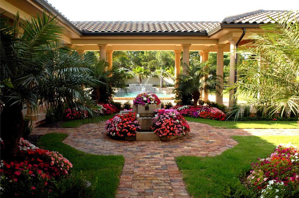 Foto di un grande patio o portico mediterraneo in cortile con fontane, pavimentazioni in mattoni e un tetto a sbalzo