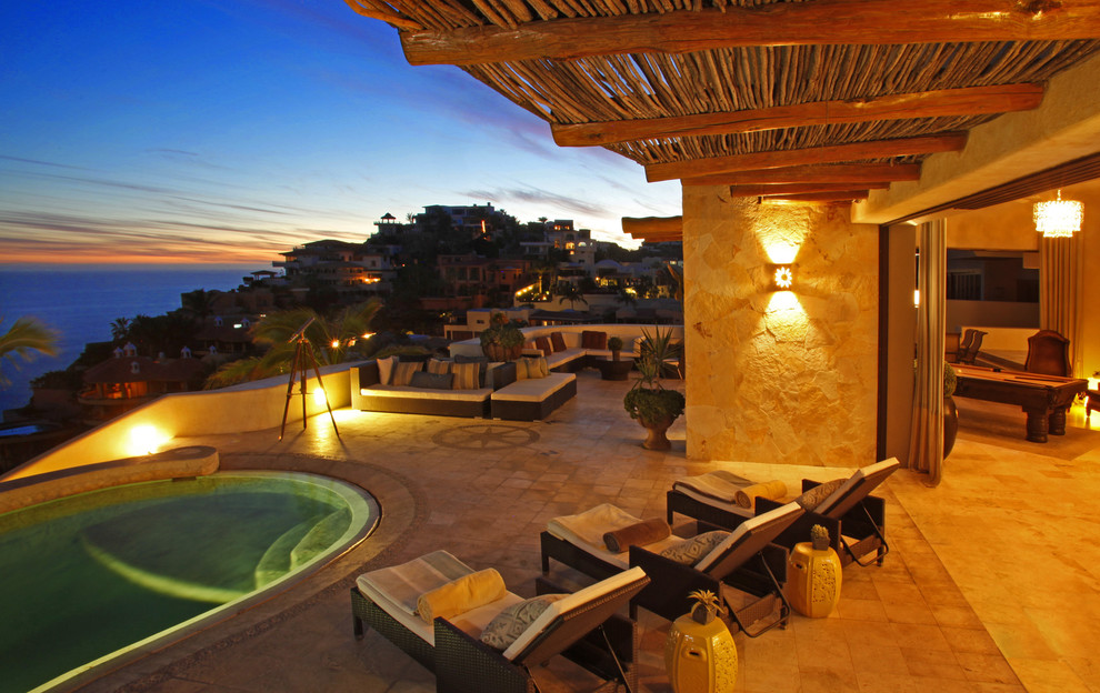 Exemple d'une grande terrasse arrière méditerranéenne avec un point d'eau, une extension de toiture et des pavés en pierre naturelle.