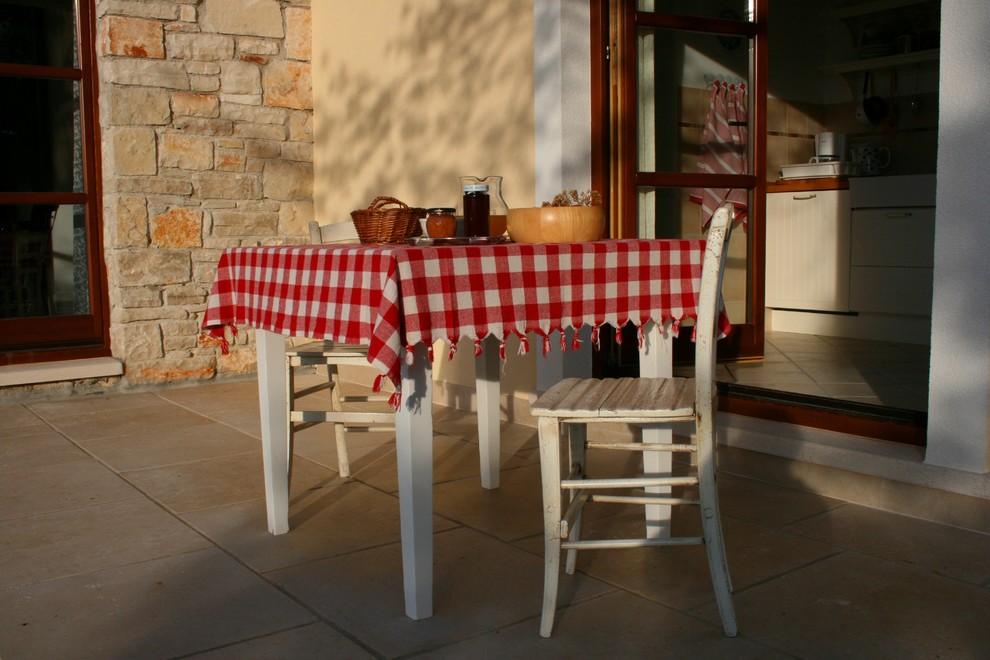 This is an example of a medium sized rural back patio with natural stone paving.