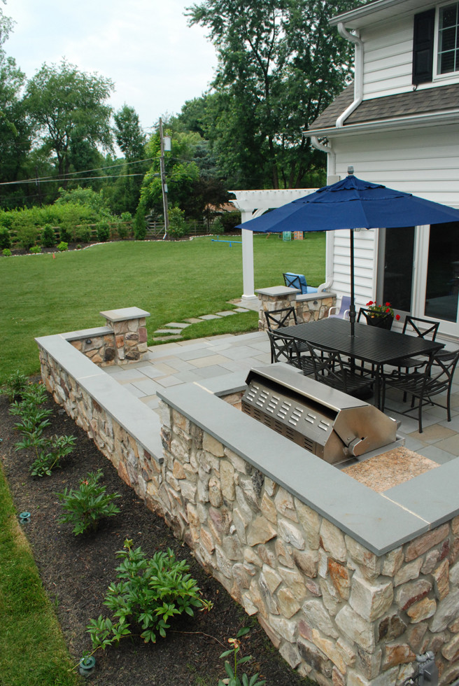 Aménagement d'une terrasse arrière classique de taille moyenne avec une cuisine d'été, des pavés en pierre naturelle et une pergola.
