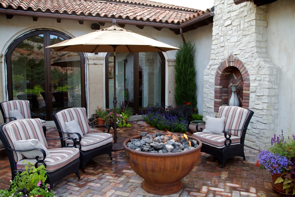 Medium sized mediterranean back patio in Denver with a fire feature, brick paving and no cover.
