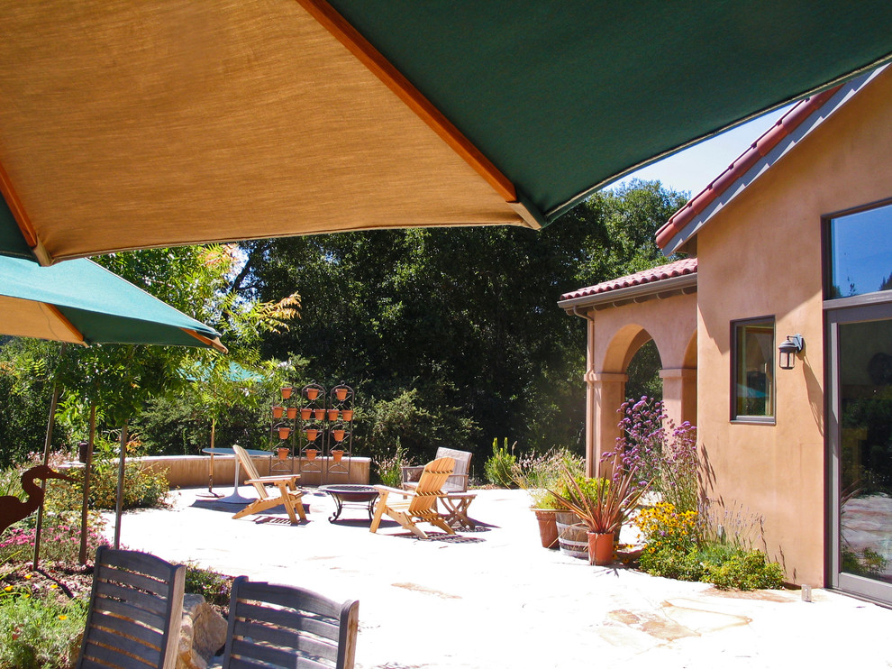 Cette photo montre une grande terrasse arrière méditerranéenne avec un foyer extérieur, des pavés en pierre naturelle et aucune couverture.