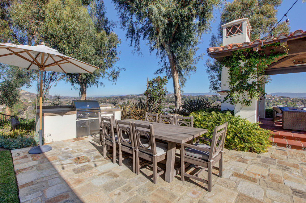 Immagine di un grande patio o portico mediterraneo dietro casa con pavimentazioni in pietra naturale, un caminetto e un gazebo o capanno