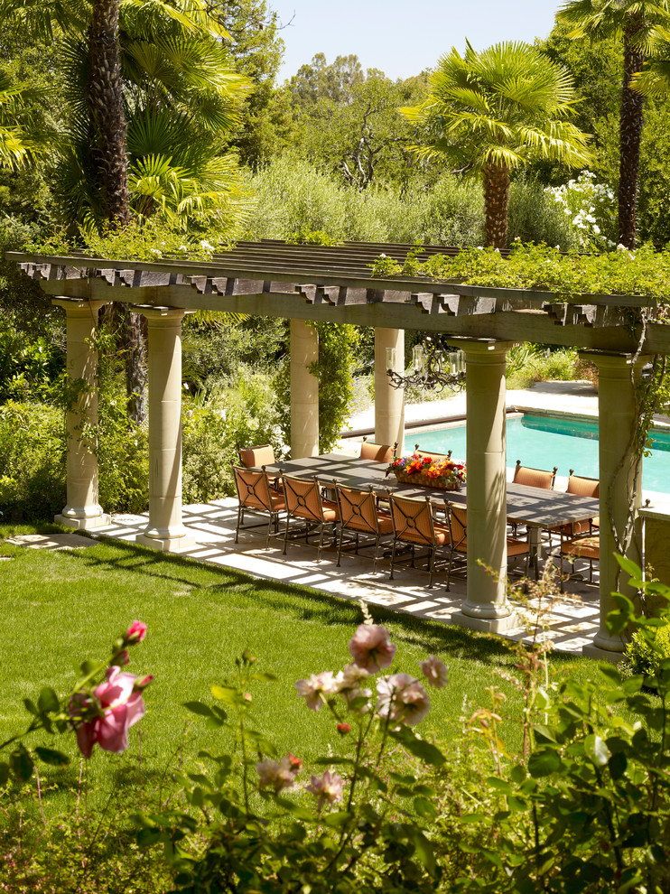 Foto di un ampio patio o portico mediterraneo dietro casa con pavimentazioni in pietra naturale e una pergola