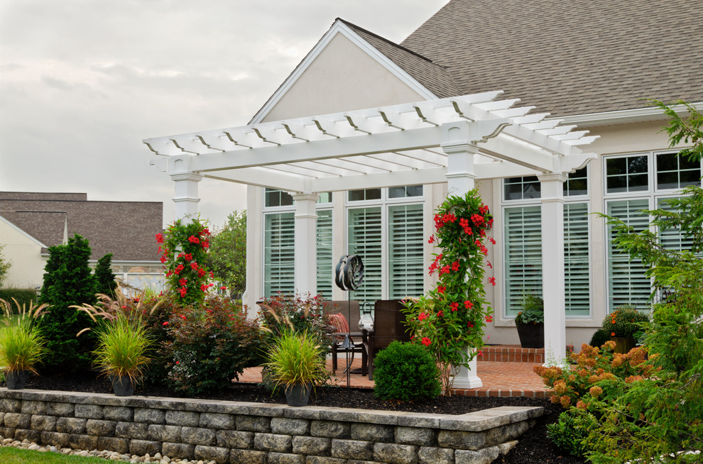 Inspiration for a mid-sized timeless backyard brick patio remodel in New York with a pergola