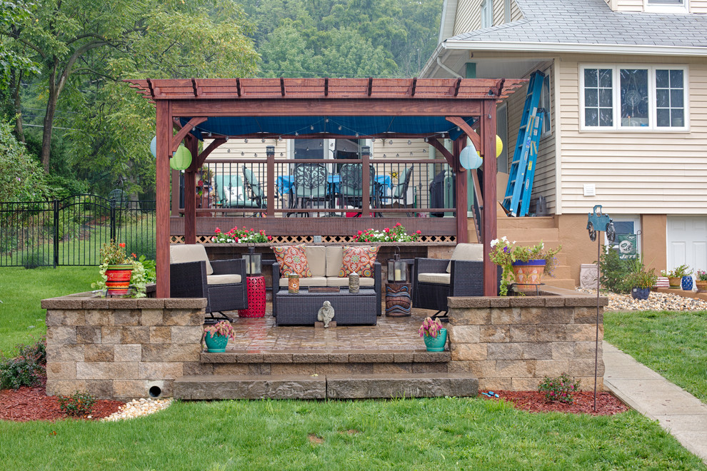 Diseño de patio tradicional renovado grande en patio trasero con adoquines de hormigón y pérgola