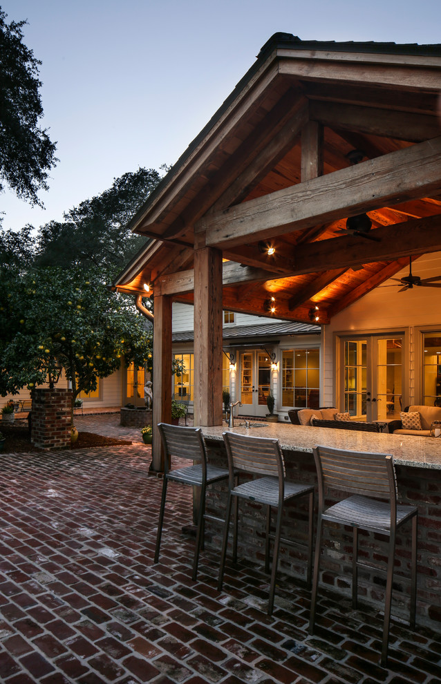 Foto di un grande patio o portico classico dietro casa con pavimentazioni in mattoni e un tetto a sbalzo
