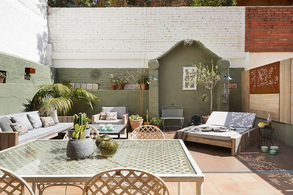 Foto di un patio o portico mediterraneo in cortile con un giardino in vaso, nessuna copertura e piastrelle