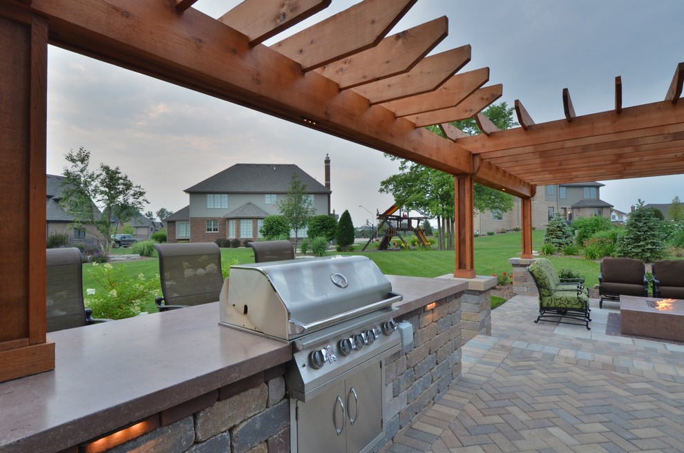 Aménagement d'une terrasse arrière classique de taille moyenne avec une cuisine d'été, des pavés en béton et une pergola.