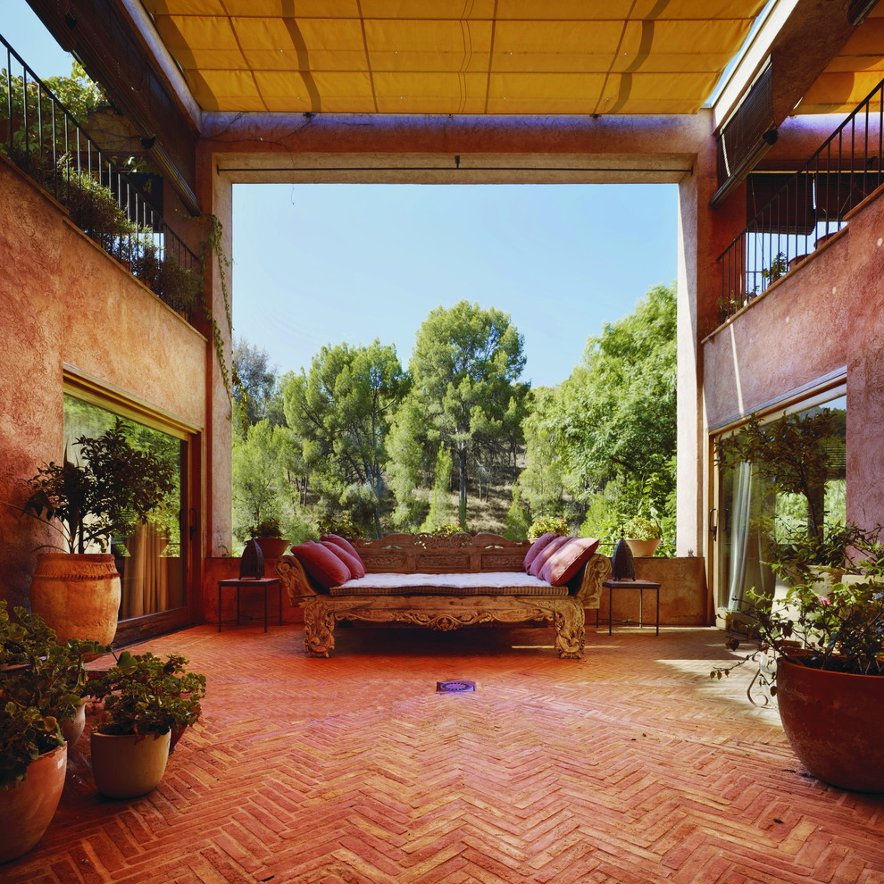 Modelo de patio de estilo de casa de campo grande con adoquines de ladrillo, toldo y jardín de macetas