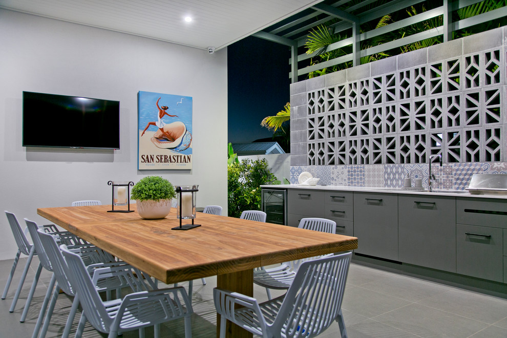 На фото: двор в современном стиле с летней кухней, покрытием из плитки и навесом с