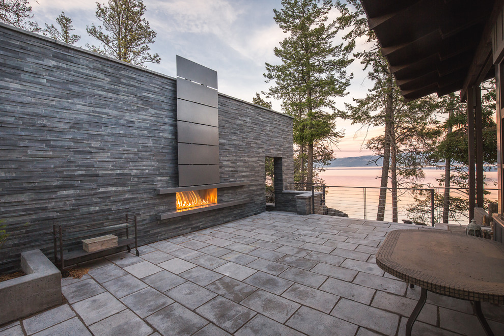 Design ideas for a rustic side patio in Other with a fireplace, concrete paving and no cover.