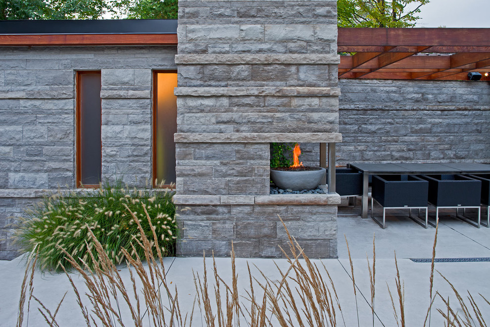 Immagine di un patio o portico minimal dietro casa con un focolare e una pergola