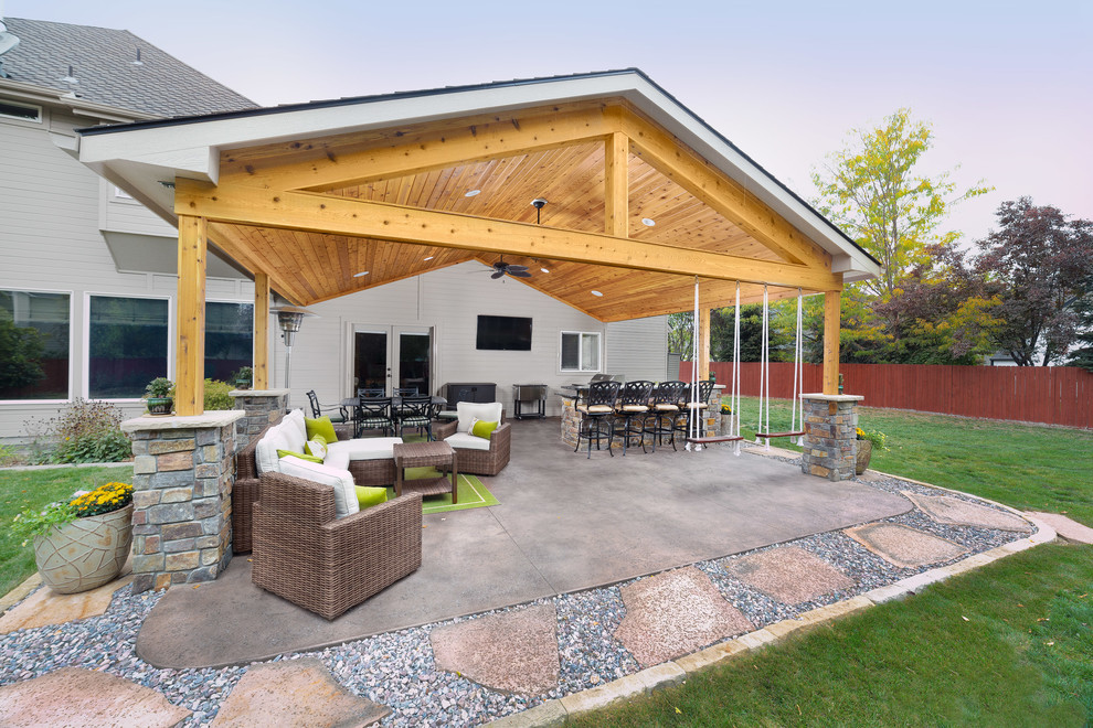 На фото: большой двор на заднем дворе в стиле неоклассика (современная классика) с летней кухней, покрытием из декоративного бетона и навесом