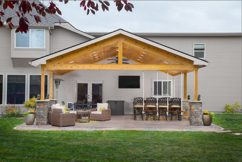 Idée de décoration pour une grande terrasse arrière tradition avec une cuisine d'été, du béton estampé et une extension de toiture.