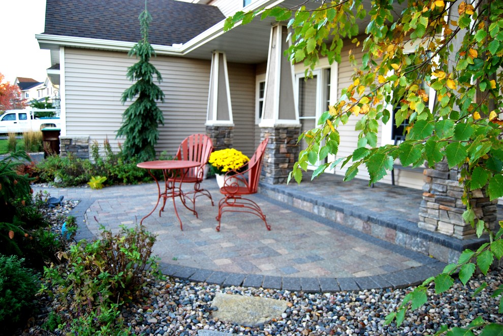 Foto di un patio o portico classico davanti casa e di medie dimensioni con pavimentazioni in mattoni, un giardino in vaso e un tetto a sbalzo
