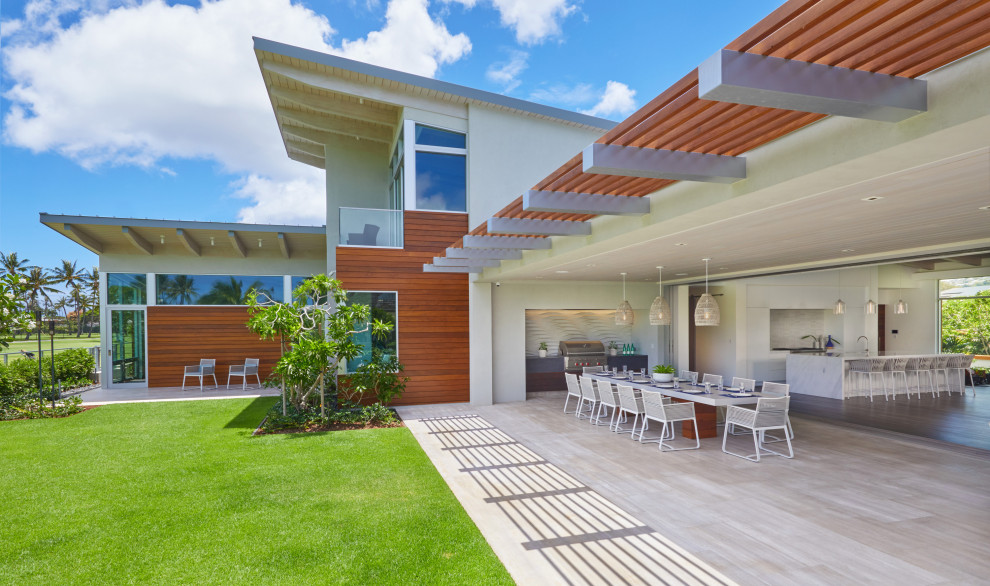 This is an example of a medium sized world-inspired back patio in Hawaii with a roof extension and a bbq area.
