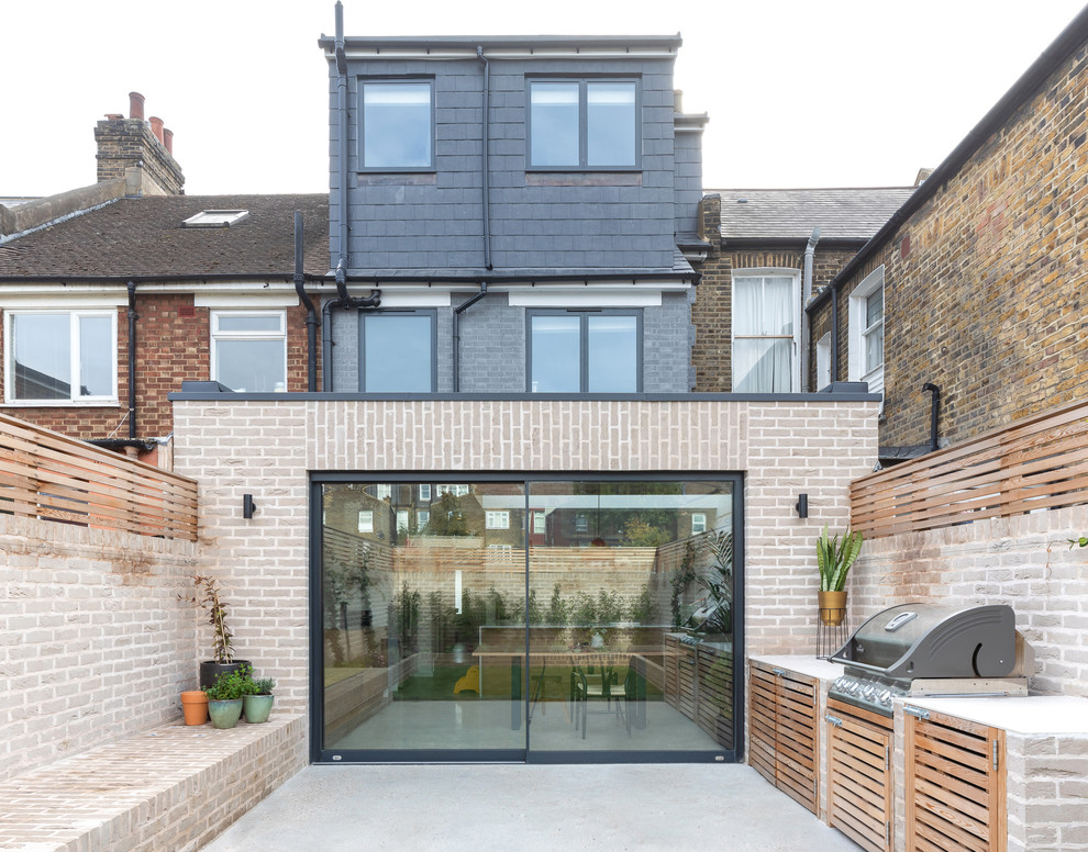 Unbedeckter Moderner Patio hinter dem Haus mit Betonplatten und Grillplatz in London