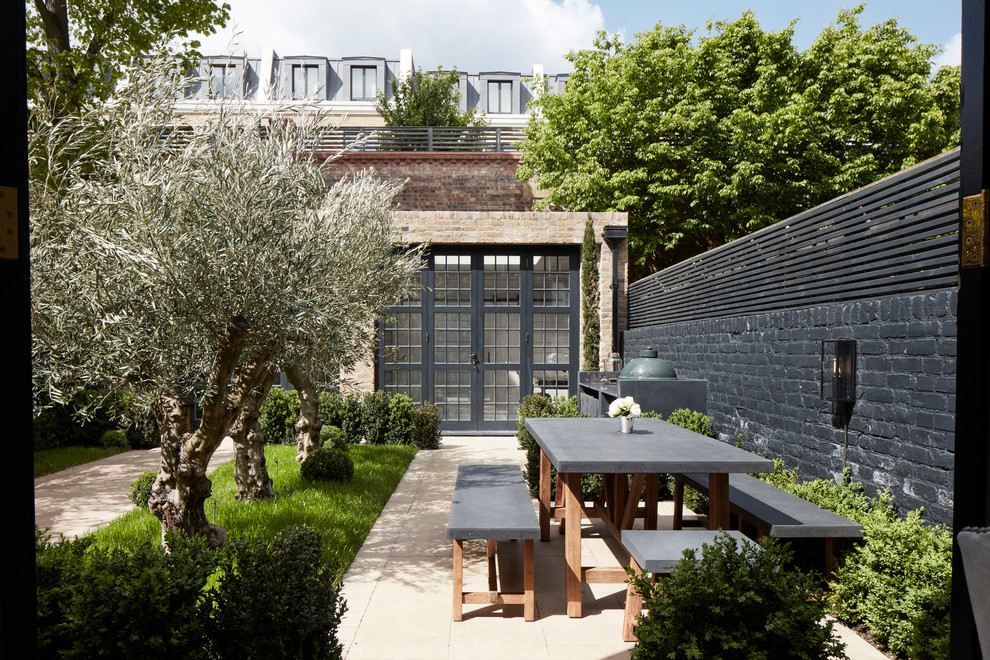 Mid-sized elegant backyard stone patio photo in London