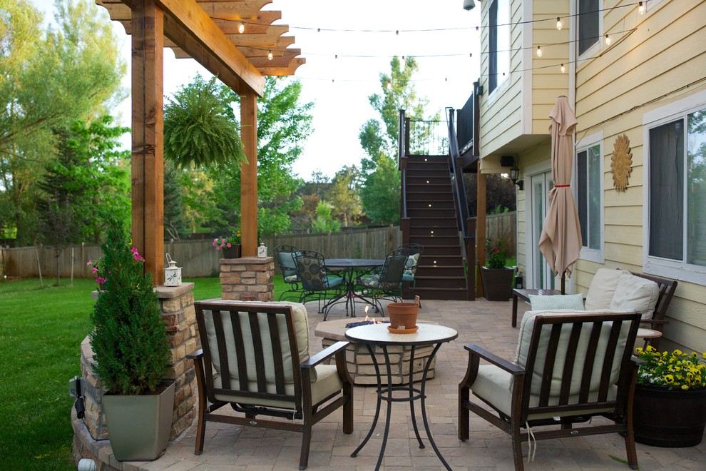 This is an example of a medium sized traditional back patio in Denver with a fire feature, brick paving and a pergola.