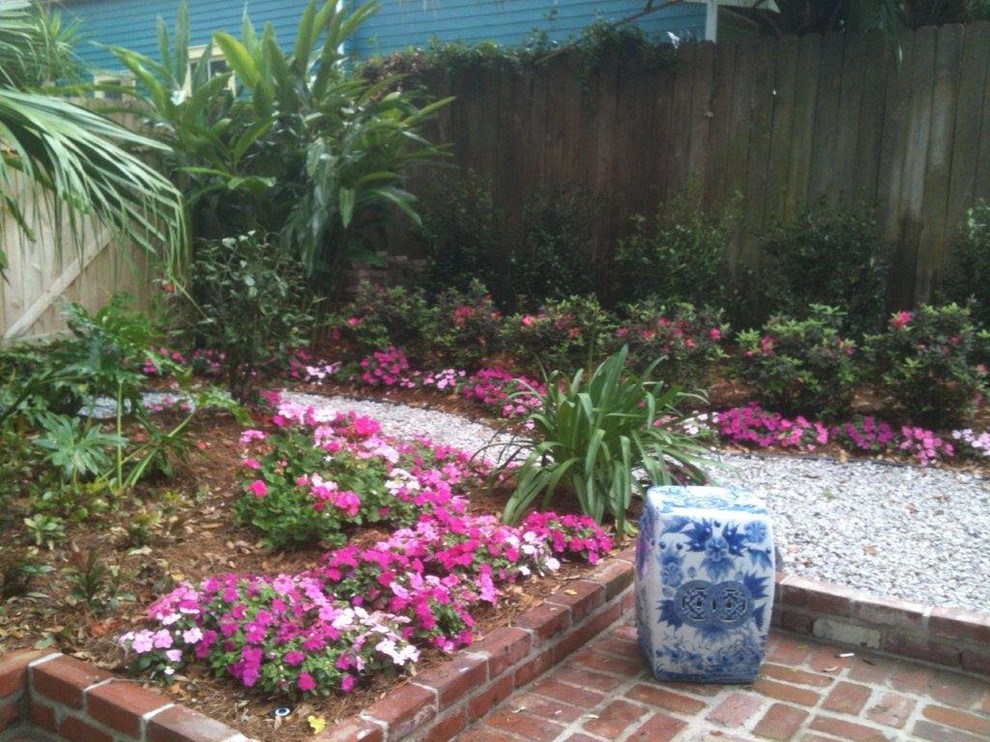 Modelo de jardín clásico de tamaño medio en primavera en patio trasero con exposición parcial al sol y adoquines de ladrillo