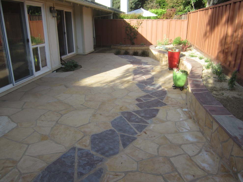 This is an example of a medium sized back patio in San Francisco with natural stone paving and a roof extension.