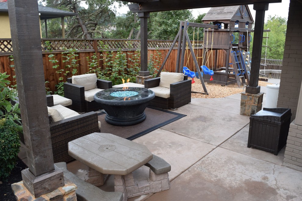 This is an example of a medium sized rustic back patio in San Francisco with a fire feature, stamped concrete and a pergola.