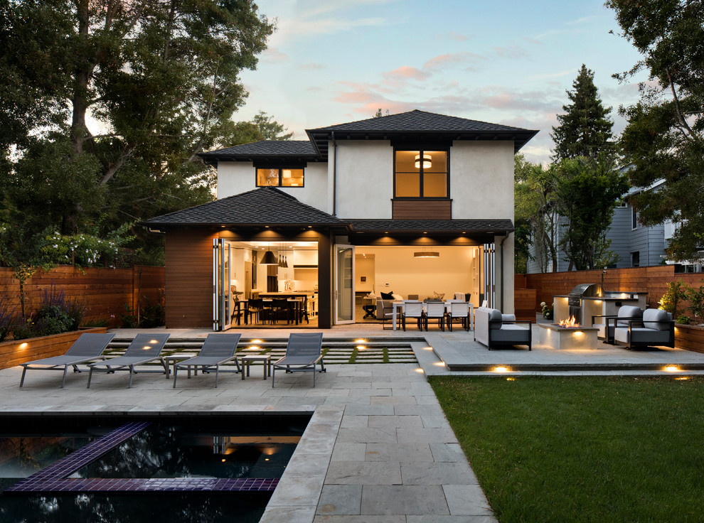 Réalisation d'une grande terrasse arrière design avec un foyer extérieur, des pavés en pierre naturelle et aucune couverture.