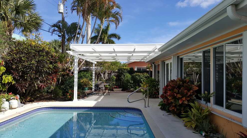 Idee per un patio o portico tropicale di medie dimensioni e dietro casa con lastre di cemento e una pergola